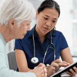 Image of clinician reviewing information on electronic tablet with patient