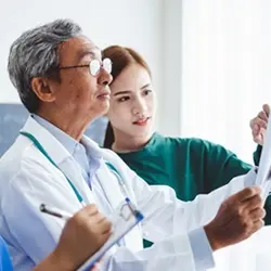 Image of clinician reviewing material with other healthcare professionals