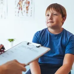 Image of pediatric patient looking at clinician in exam room