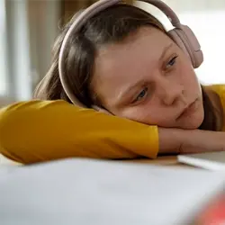Image of adolescent resting head on arms and looking sleepy